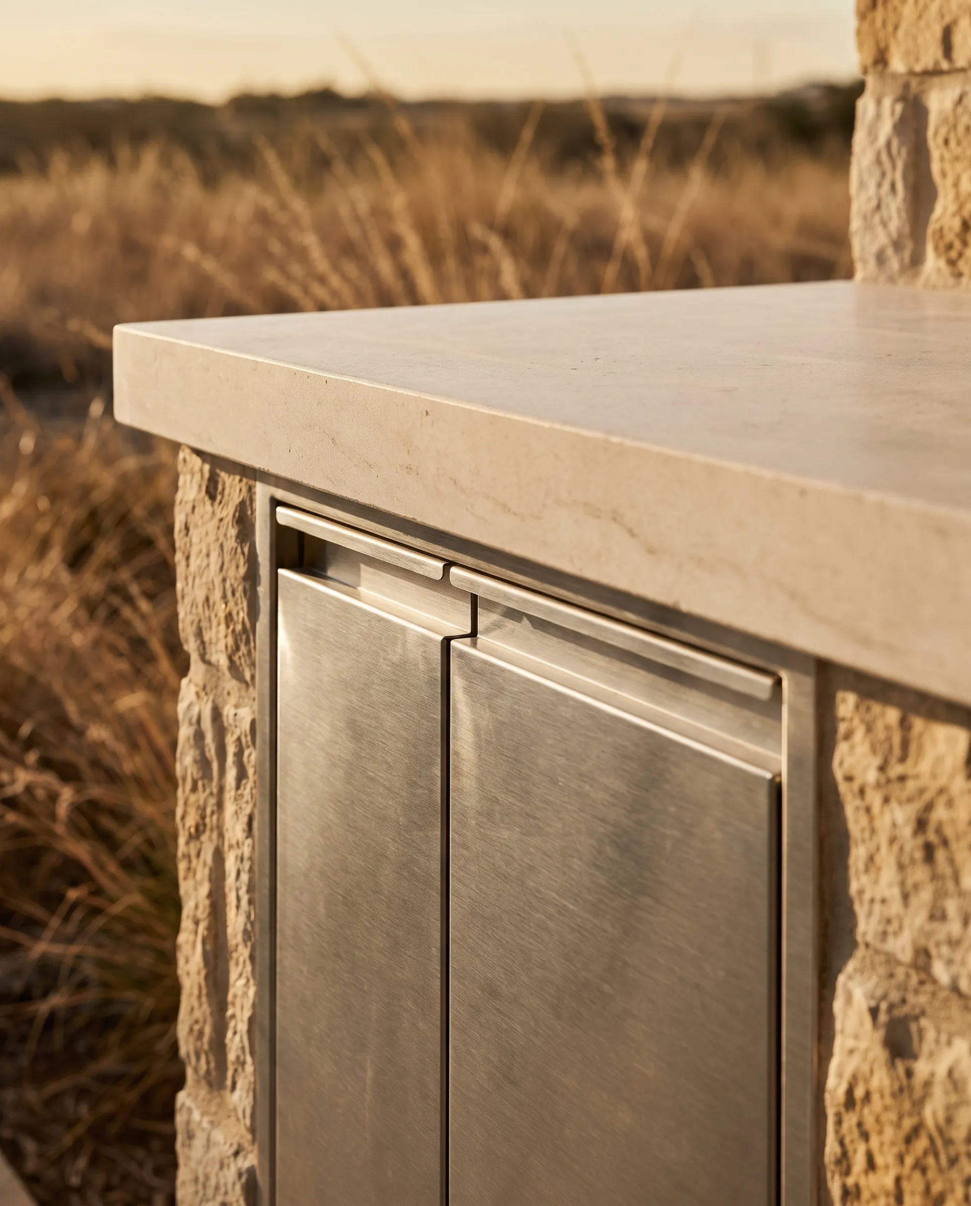Close detail of brushed stainless cabinet fronts and stone counter